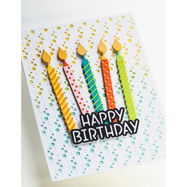 A white birthday card featuring five colorful candle-shaped decorations with yellow flames and the words 'HAPPY BIRTHDAY' in black letters with white outlines, set against a background of small yellow and blue dots.