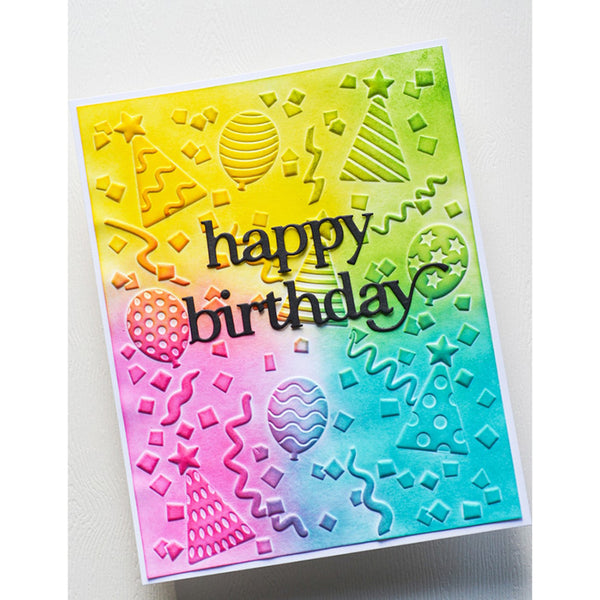 A handmade birthday card with a vibrant yellow-to-blue gradient background, featuring embossed party-themed designs like balloons, stars, and party hats. The words 'happy birthday' are written in black cursive across the center.