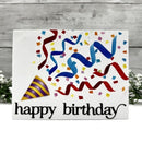 A square white birthday card with colorful confetti, ribbon streamers, a party hat, and the words 'happy birthday' in black script, displayed against a gray wood-plank background with small white flowers at the sides.