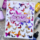 A handmade white card featuring colorful butterfly cutouts and a raised 'happy birthday' text element, surrounded by craft supplies including alcohol ink bottles and Maxin art media.