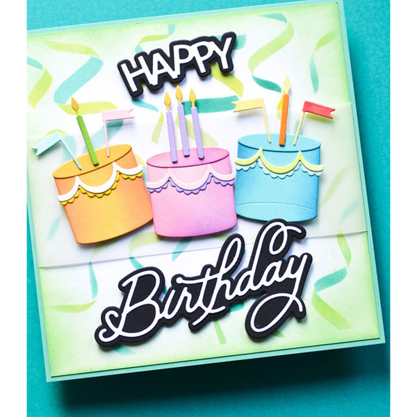 A square handmade greeting card or gift box featuring three colorful birthday cakes with candles, the words 'HAPPY Birthday' in layered black-and-white script, and a light green confetti pattern on a turquoise background.