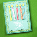 A handmade birthday card with five colorful paper candles and the words 'make a Wish' in white script, displayed on a textured green background.