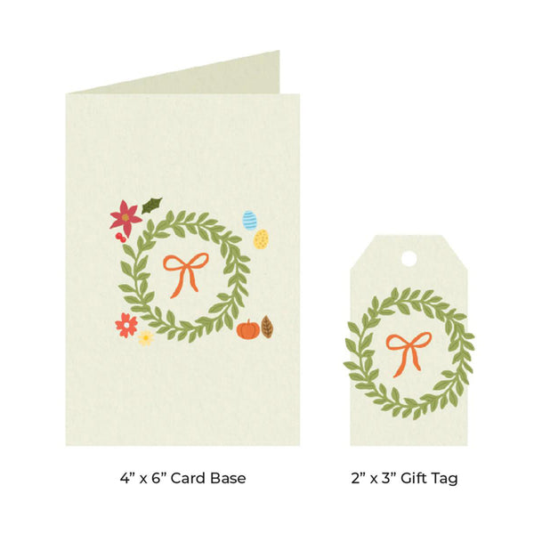 A card base and matching gift tag set with a green wreath design, orange bow, and small floral accents on a white background. Text below reads '4" x 6" Card Base' and '2" x 3" Gift Tag'.