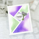 A handmade greeting card with a white border, featuring a geometric design in purple and light green with a small bouquet illustration and the text 'THANKS a bunch!'.