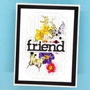 A handmade layered card featuring the word 'friend' in black script over a white background with butterfly and floral cutouts, set against a light blue backdrop.