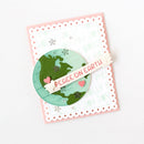 A handmade greeting card featuring a scalloped pink border, a white center with faint holiday text, and a layered circular globe design in green and mint with the phrase 'PEACE ON EARTH' on a banner.