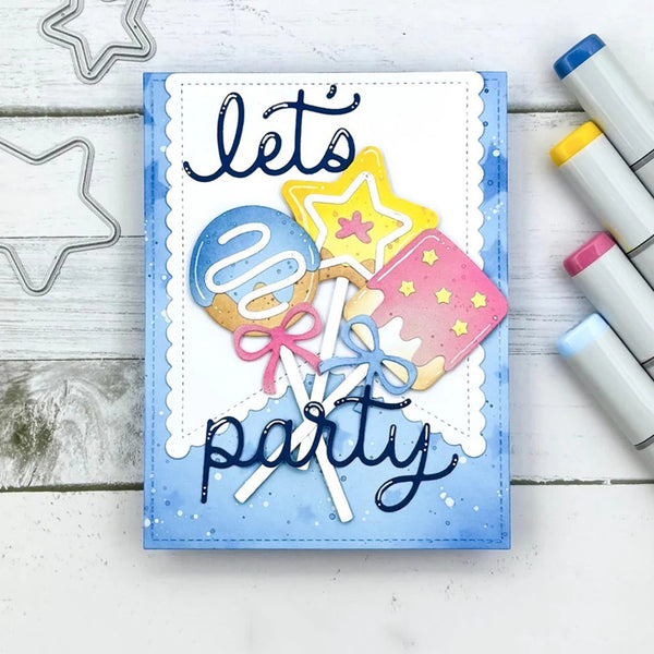 A handmade paper card with the words 'let's party' in dark blue script, decorated with layered lollipop and star illustrations in pastel blue, yellow, pink, and white. The card is photographed on a white wood surface with star-shaped metal cutouts and colored markers nearby.