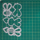 A set of clear plastic craft die-cutting templates shaped like a bee, a gingerbread man, a pear, a pear with a leaf, and a bow, arranged on a green cutting mat with grid lines.