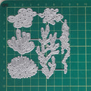 A set of silver metal die-cut craft shapes featuring coral and seaweed designs, displayed on a green cutting mat with grid lines and centimeter measurements.