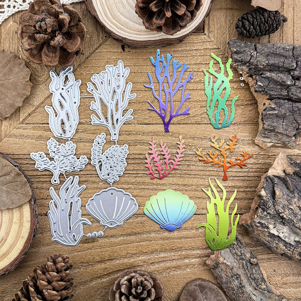 A set of colorful coral and shell-shaped metal cutting dies arranged on a rustic wooden surface with pinecones and wood slices as props.