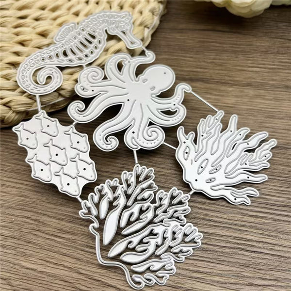 Silver metal die-cut craft embellishments featuring an octopus, seahorse, coral, and fish designs, arranged on a wooden surface with a woven straw prop.