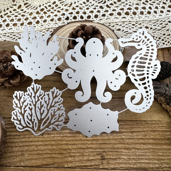 White metal laser-cut wall art featuring an octopus, seahorse, coral, and fish silhouette, arranged on a rustic wooden surface with a lace doily and pinecones in the background.