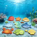 A colorful underwater-themed children's toy set featuring cartoon sea creatures and shells, including an octopus, starfish, fish, whale, seahorse, crab, turtle, and shell, arranged on a sandy ocean floor with coral and seaweed.