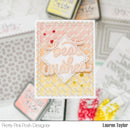 A handmade greeting card with layered die-cut elements reading 'Best wishes' in pink script over a white diamond, set against a patterned peach and yellow background with confetti accents. The card is photographed in a styled flat-lay with blurred craft ink pads and cards around it.