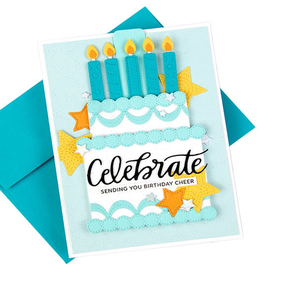 A handmade layered birthday card featuring a tiered cake with five blue candles, yellow glitter stars, and the text 'Celebrate Sending You Birthday Cheer', shown with a teal envelope on a white background.