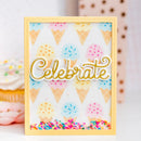 A square handmade greeting card with a yellow border, featuring a white background decorated with colorful ice cream cone illustrations, a large gold foil 'Celebrate' script across the center, and multicolored sprinkles along the bottom edge. The card is displayed in a soft-focus setting with cupcakes in the background.