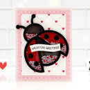 A handmade Valentine's Day ladybug card featuring a red and black ladybug with glitter-filled spots, a white banner reading 'VALENTINE GREETINGS', and a pink scalloped border on a white background.