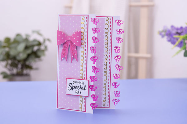 A handmade greeting card with pink and white polka dot patterns, a pink bow, and the text 'ON YOUR Special DAY' on a lavender surface with a blurred indoor background.