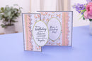 Decorative birthday card with floral and ribbon design on a blue surface.