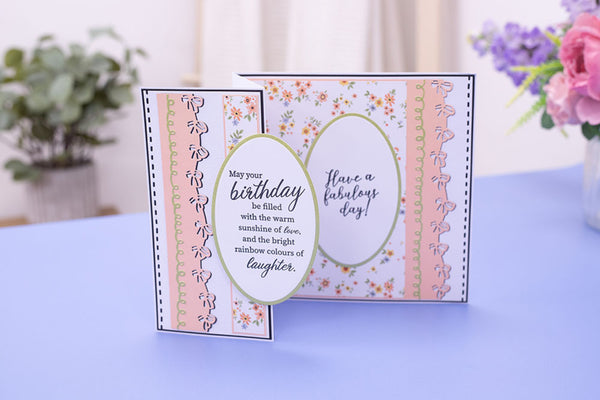 Decorative birthday card with floral and ribbon design on a blue surface.