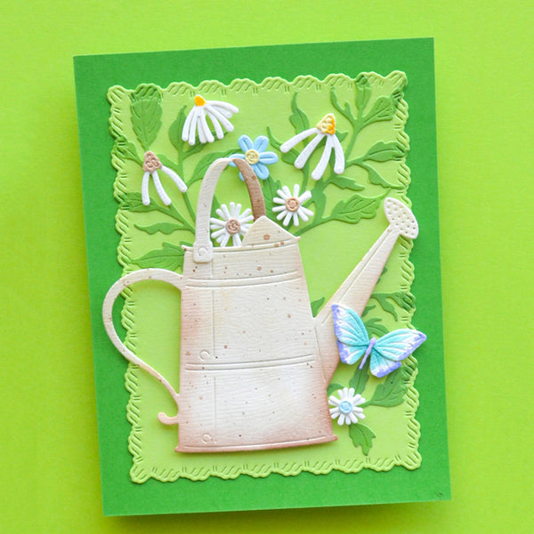 A handmade layered paper card featuring a 3D embossed watering can, white and blue daisies, green leaves, and a blue butterfly on a bright green background, set against a solid lime green backdrop.