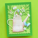 A handmade layered paper card featuring a 3D embossed watering can, white and blue daisies, green leaves, and a blue butterfly on a bright green background.