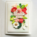A handmade layered paper card featuring the words 'thank you' in raised white letters, surrounded by colorful paper flowers and leaves in red, pink, green, and white, set against a textured cream cardstock background.