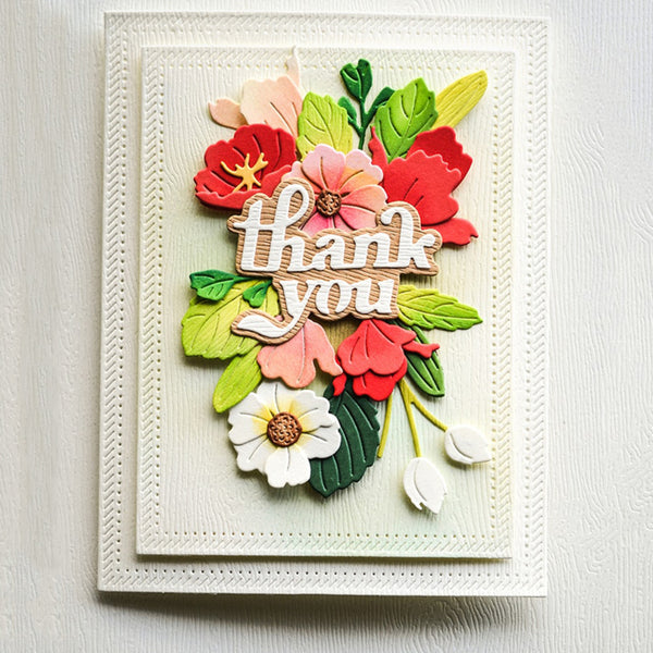 A handmade 3D card featuring layered paper flowers and leaves with a wooden 'thank you' message, displayed on a textured white background.