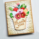 A handmade square greeting card featuring a 3D floral arrangement in a beige pot with the words 'thank you' in script, photographed on a light gray textured background.