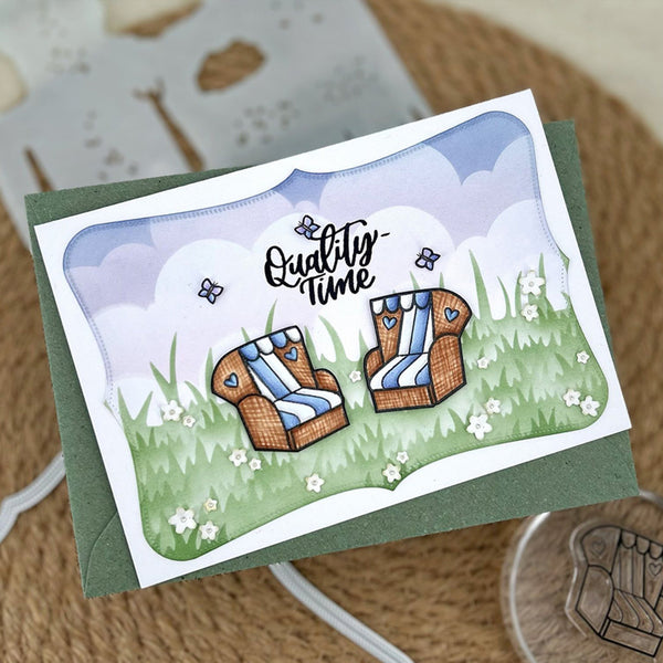 A handmade greeting card with a green envelope, featuring an illustration of two wicker beach chairs with blue and white striped cushions in a grassy field with the words 'Quality time' written above.