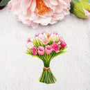 A watercolor-style bouquet illustration of pink tulips and white blossoms with green leaves, tied with a peach band, placed on a textured white background with partial pink flowers at the top.