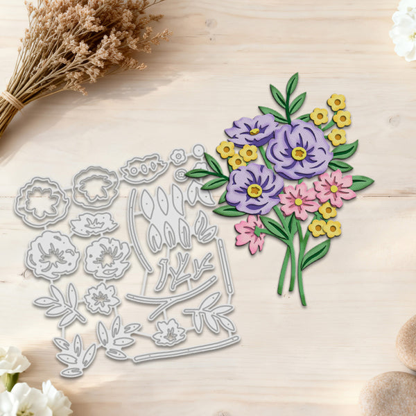 A floral die-cut craft set displayed on a light wood surface, featuring a silver metal cutting template on the left and a matching paper cutout bouquet on the right with purple, pink, and yellow flowers and green leaves.