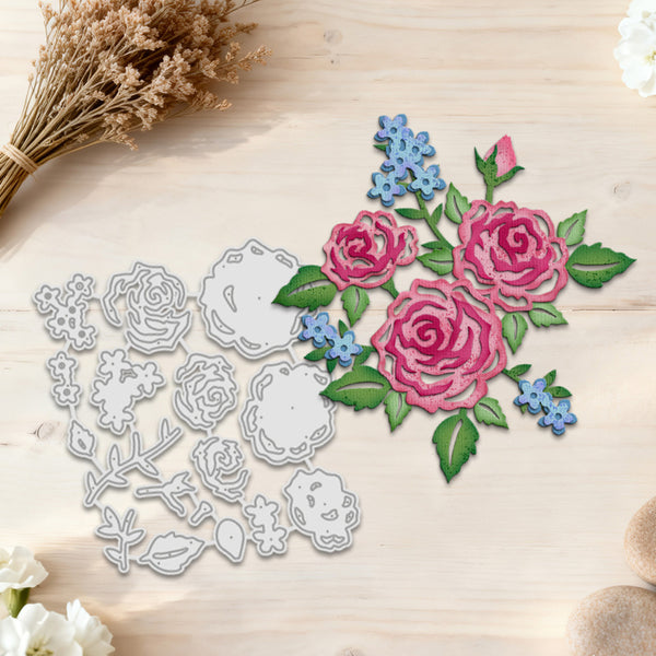 A floral die-cut craft set displayed on a light wood surface, featuring a silver metal cutting-matrix layout on the left and matching embroidered rose and blue flower appliques on the right.