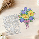 A floral die-cut craft set displayed on a light wood surface, showing both the silver metal cutting template and the colorful layered paper bouquet pieces, including yellow and purple flowers, green leaves, and a pink ribbon.