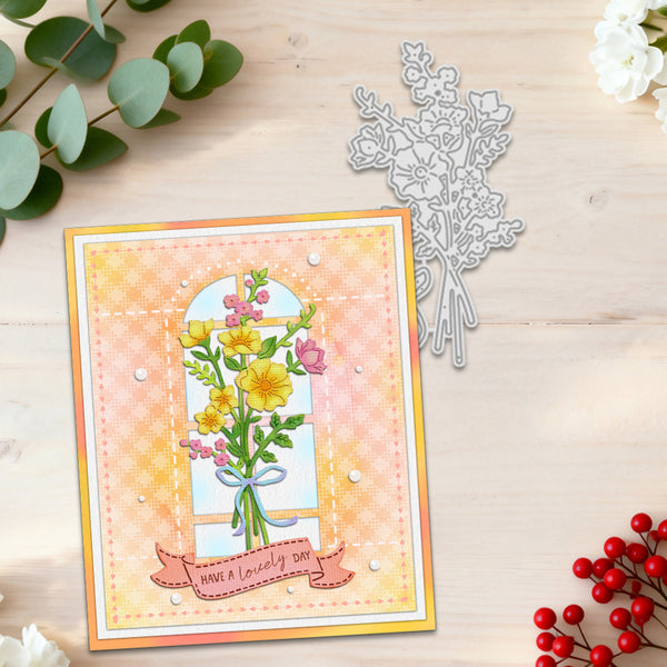 A handmade greeting card with a floral window illustration and the text 'HAVE A lovely day' is displayed on a light wood surface alongside a silver floral die-cutting template, green eucalyptus leaves, and red berries.