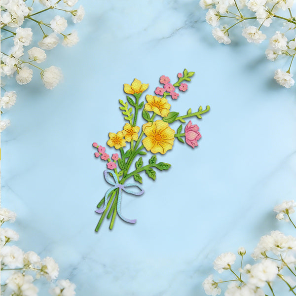 A colorful embroidered floral bouquet patch featuring yellow and pink flowers with green leaves and a purple ribbon, displayed on a light blue marble background with white baby's breath flowers framing the edges.