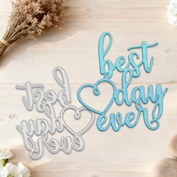 Decorative metal cutouts with 'it was a good world to live in' and 'best day ever' text on a wooden surface with flowers.