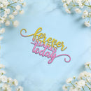 A decorative script sign reading 'forever starts today' in yellow, pink, and orange gradient lettering, placed on a light blue marble surface with white flowers framing the corners.