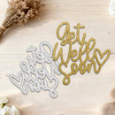 Metal cutting dies with 'Get Well Soon' text on a wooden surface with flowers.
