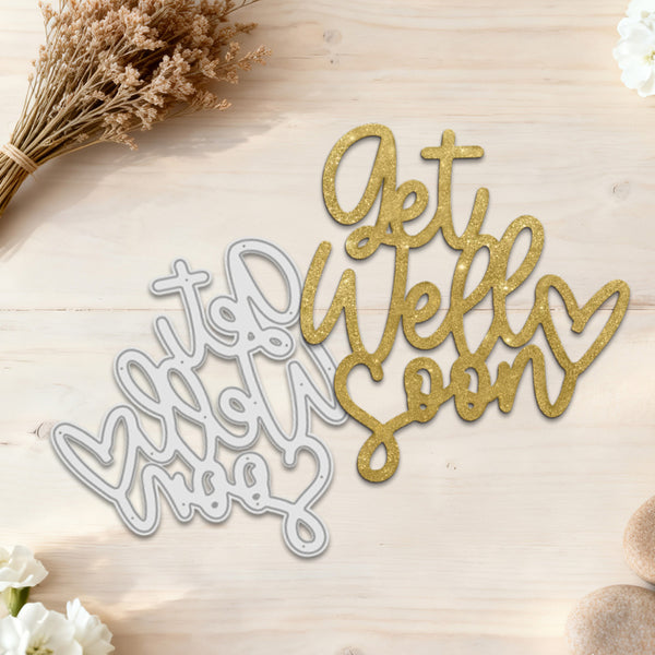 Metal cutting dies with 'Get Well Soon' text on a wooden surface with flowers.