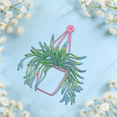 A decorative hanging planter silhouette with layered green foliage and a pink outline, centered on a light blue marble background with white baby's breath flowers around the edges.