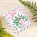 A handmade greeting card featuring a pink and white gingham pattern, a green hanging plant illustration, and the text 'Hollylyah' in pink script. The card is styled on a light wood surface with green fern leaves in the corners.