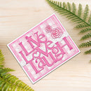 A handmade greeting card with the words 'Live Laugh Love' in pink layered letters over a pink and white gingham pattern, decorated with two 3D roses and small pearl accents, displayed on a light wood background with green fern leaves.