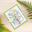 A handmade Mother's Day greeting card with a floral design, placed on a light wood surface with green fern leaves around it. The card features pink daisies, green stems, a pink bow, and the text 'Happy Mother's Day'.