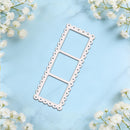 A single rectangular metal die-cut template with scalloped edges and three rounded rectangular sections, displayed on a light blue marble background with white baby's breath flowers in the corners.
