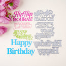 A flat lay of decorative birthday-themed lettering and die-cut shapes on a light cream background, with pink flowers in the top-left corner. The designs include pink, light pink, light green, and bright blue script text such as 'Hip Hip HOORAY!', 'NOT OLDER Just Better', 'RELATED Birthday Wishes', and 'Happy Birthday', alongside matching gray metal die-cut outlines.