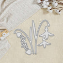 A metal die-cut craft cutting tool set shaped like lily of the valley flowers and a jellyfish, displayed on a textured cream background with cotton stems and a wooden-handled cutting mat partially visible.