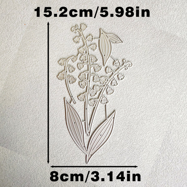 A floral die-cut stamp or embossing template showing a lily-of-the-valley design on textured off-white paper, with dimension labels reading 15.2cm/5.