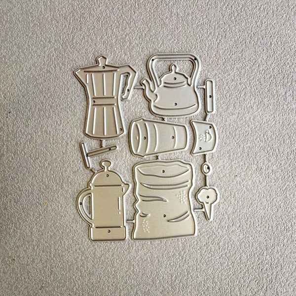 A set of six metal cookie cutters shaped like coffee and tea vessels, including a moka pot, teapot, coffee bean bag, French press, mug, and cup, arranged on a textured light beige surface.