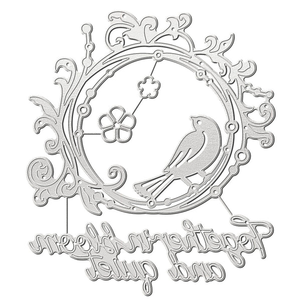 A silver metal die-cut decorative piece featuring a bird, floral motifs, and cursive script text on a plain white background.